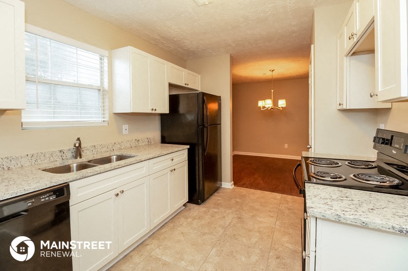 a kitchen with white cabinets and a black refrigerator