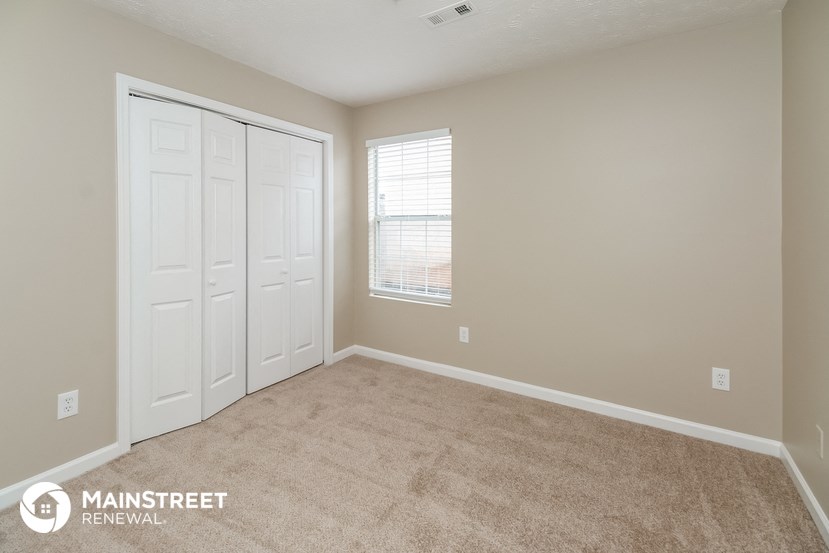 a bedroom with a carpeted floor and two doors and a window