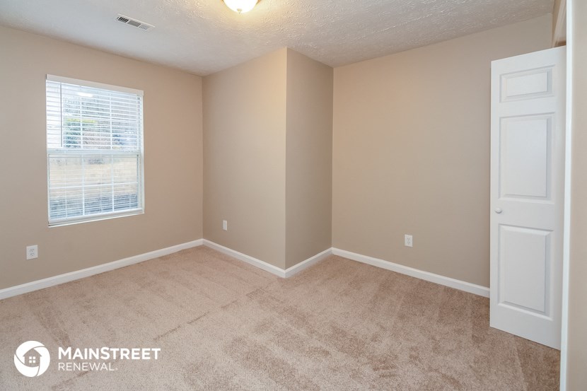 the upstairs bedroom with carpeted flooring and a white door