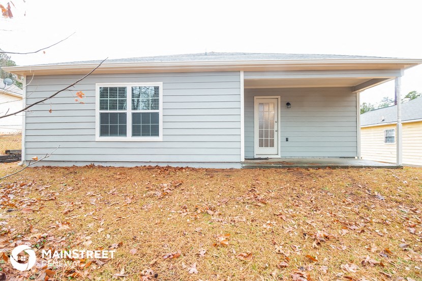 a small house with a front porch and a yard with fallen leaves