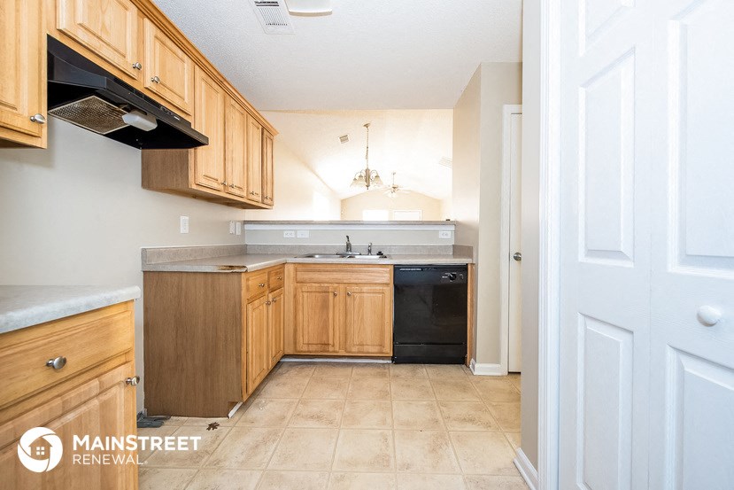 a small kitchen with wooden cabinets and a black dishwasher