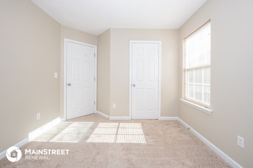 an empty living room with two doors and a carpeted floor