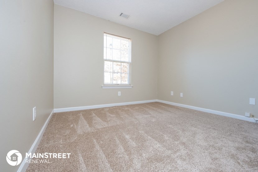 a large empty room with carpet and a window