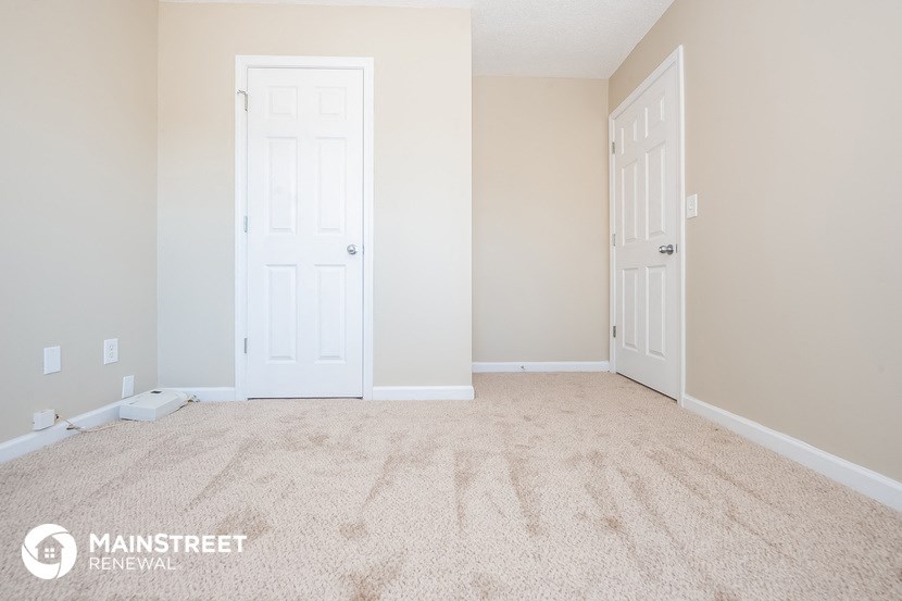 a empty room with two doors and a carpeted floor