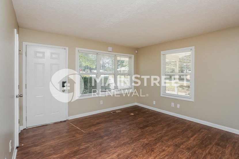 an empty living room with a white door and wood floors