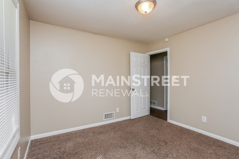 a bedroom with a carpeted floor and a door to a closet