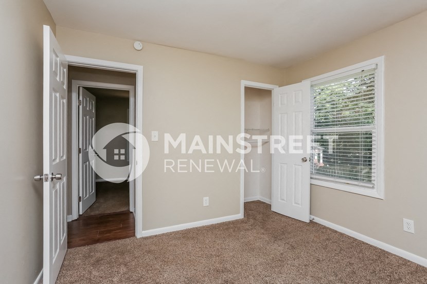 a bedroom with a door to a hallway and a window