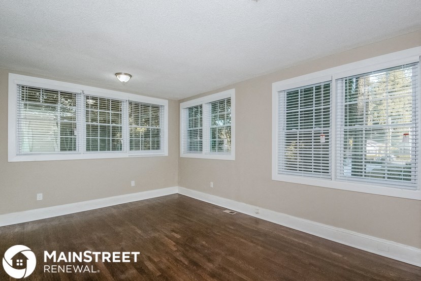 the spacious living room with wood floors and windows