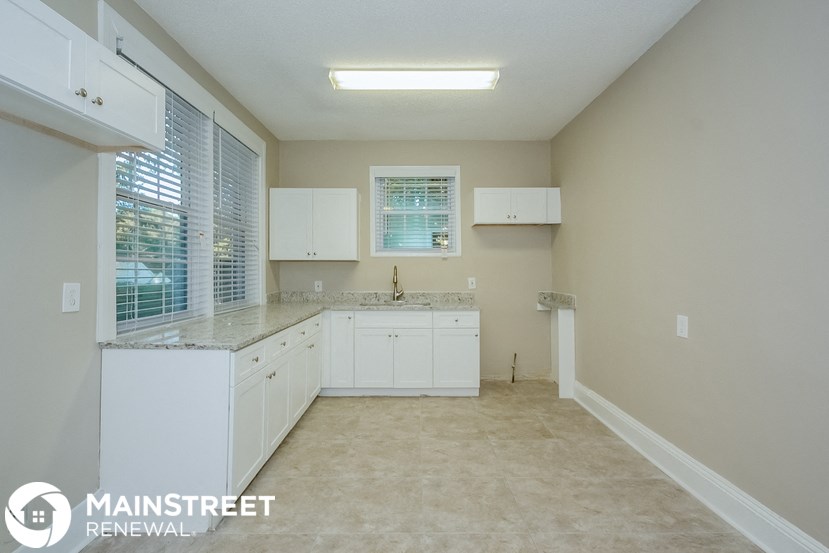 a large white kitchen with white cabinets and a window