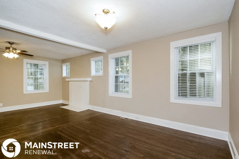 the living room of an empty home with wood flooring and a ceiling fan