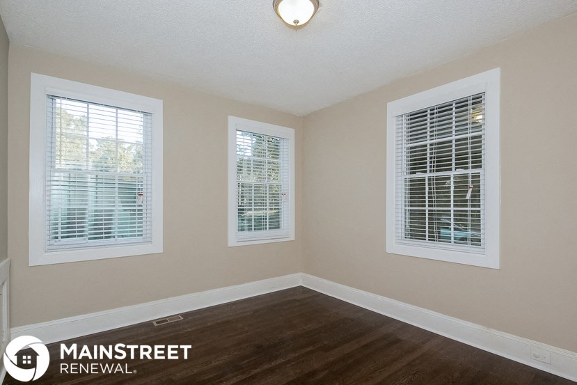a living room with a hard wood floor and three windows