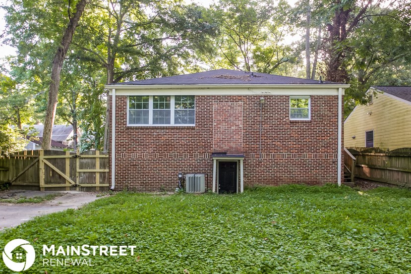 the front of a brick house with a yard and a wood fence