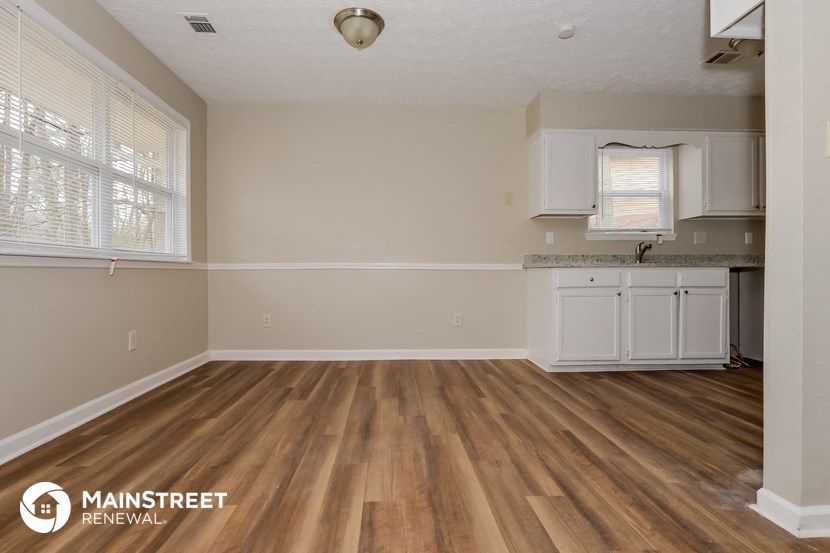 the kitchen and living room of a renovated house with wood flooring
