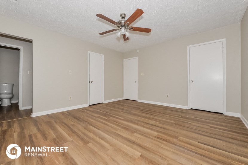 the spacious living room with hardwood flooring and a ceiling fan