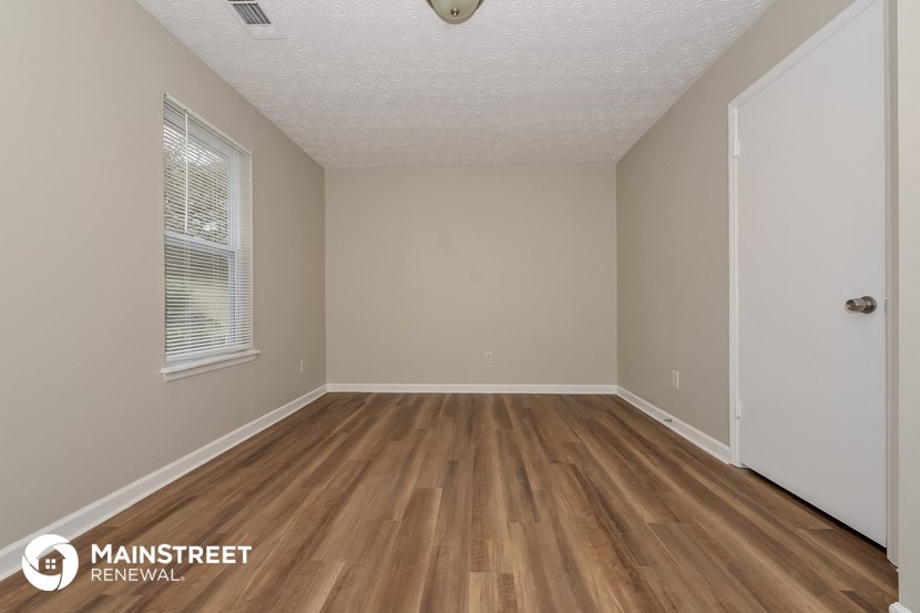 the interior of an empty room with wood flooring and a window