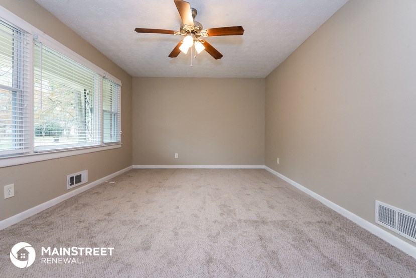 the master bedroom is spacious and clean with a ceiling fan and a large window