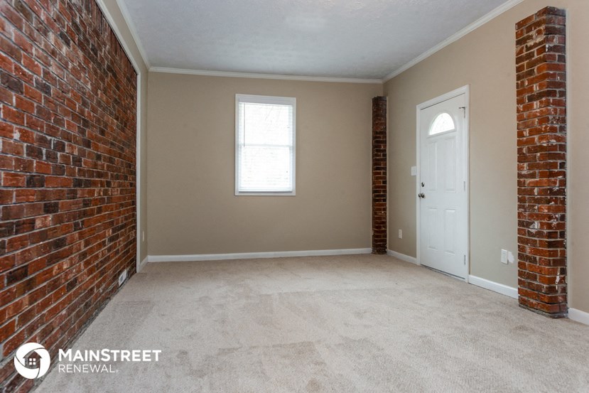 an empty room with a brick wall and a white door