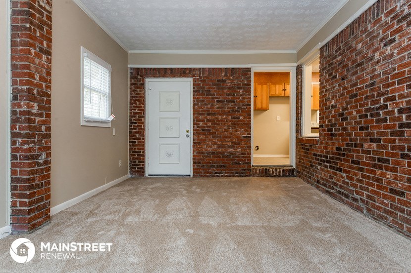an empty living room with a brick wall and a white door