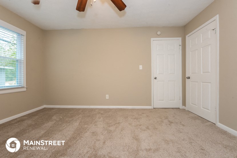 the living room of a home with carpet and two doors