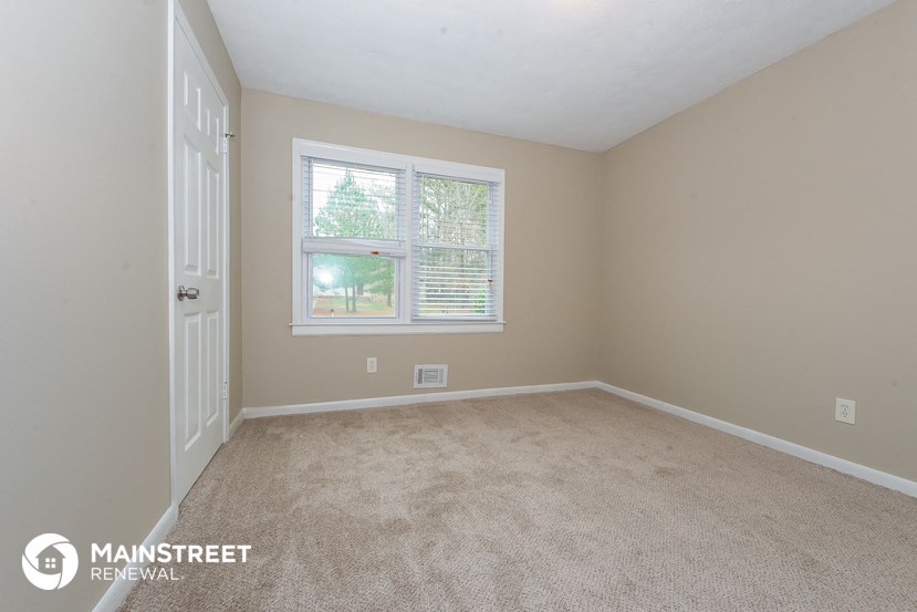 the bedroom of a rental home with carpet and a window
