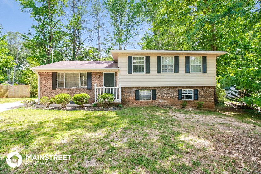a white and brick house with green shutters and a lawn
