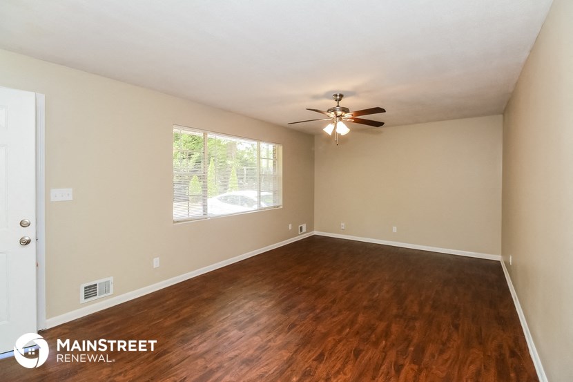 the spacious living room with hardwood flooring and ceiling fan