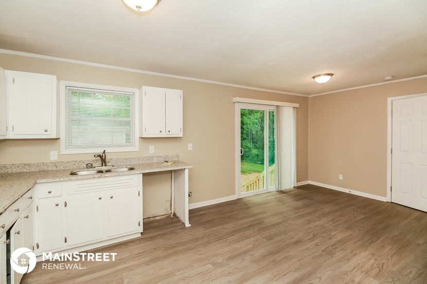 the kitchen and living room of a house with white cabinets