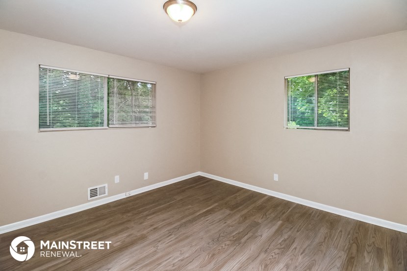 the spacious living room with hardwood flooring and two windows