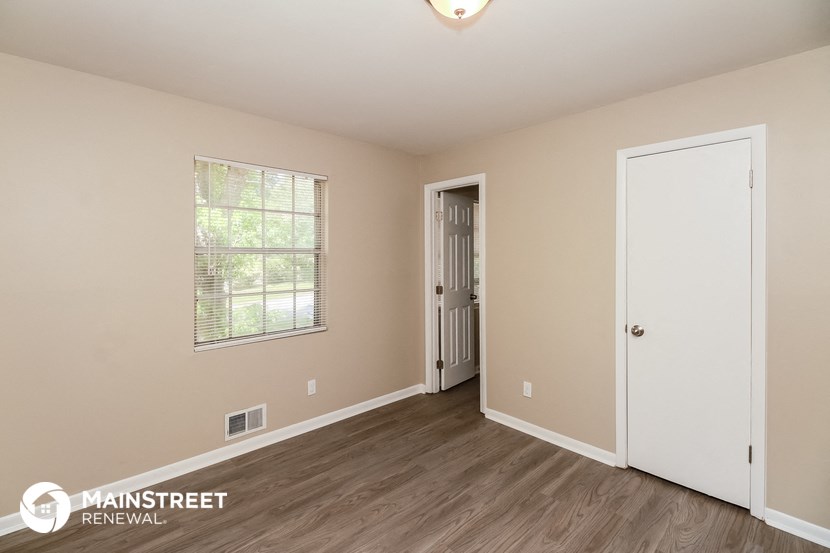 the living room of an apartment with wood flooring and a white door