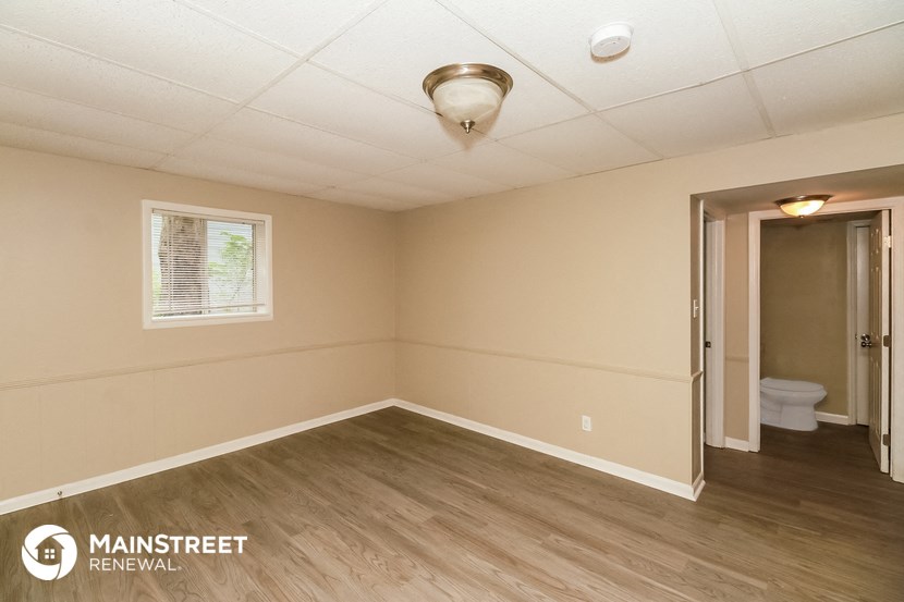the interior of an empty room with wood flooring and a toilet