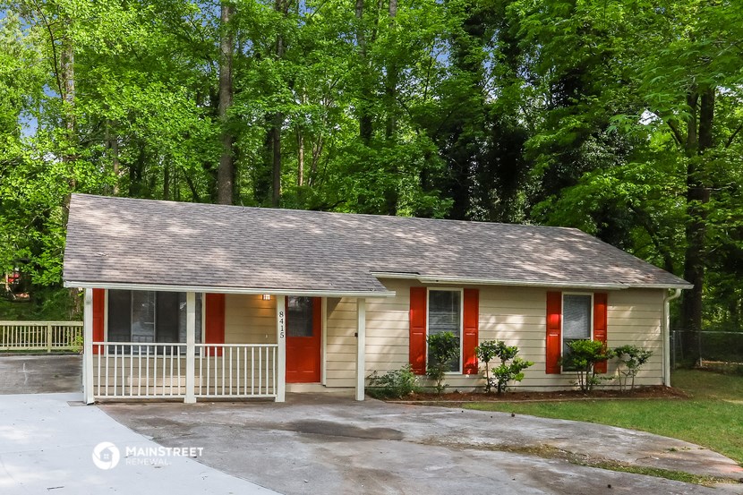 a small yellow house with red doors and a porch
