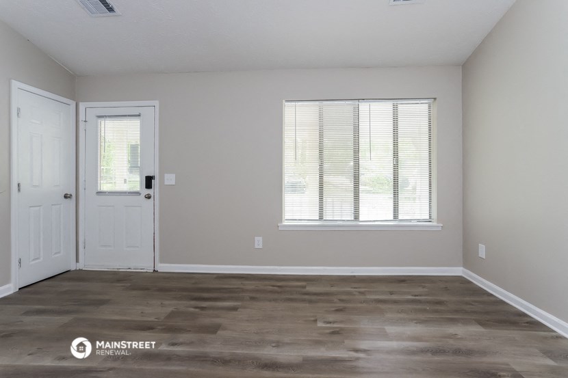 an empty living room with a white door and window