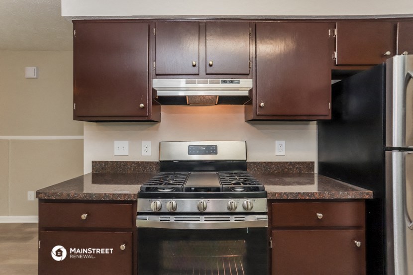 a kitchen with a stove and cabinets and a refrigerator