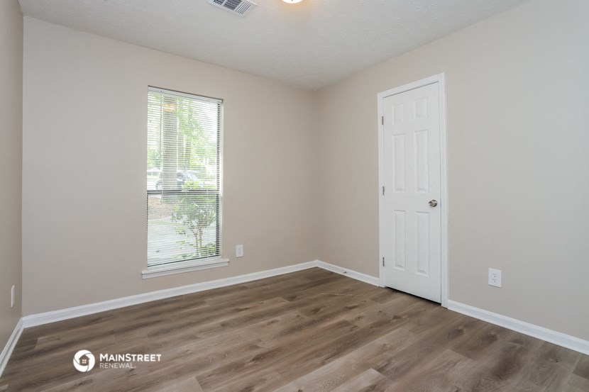 the interior of a bedroom with wood flooring and a window