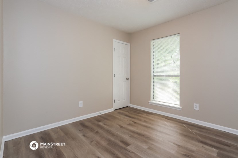 a bedroom with a door and a window and wooden floors