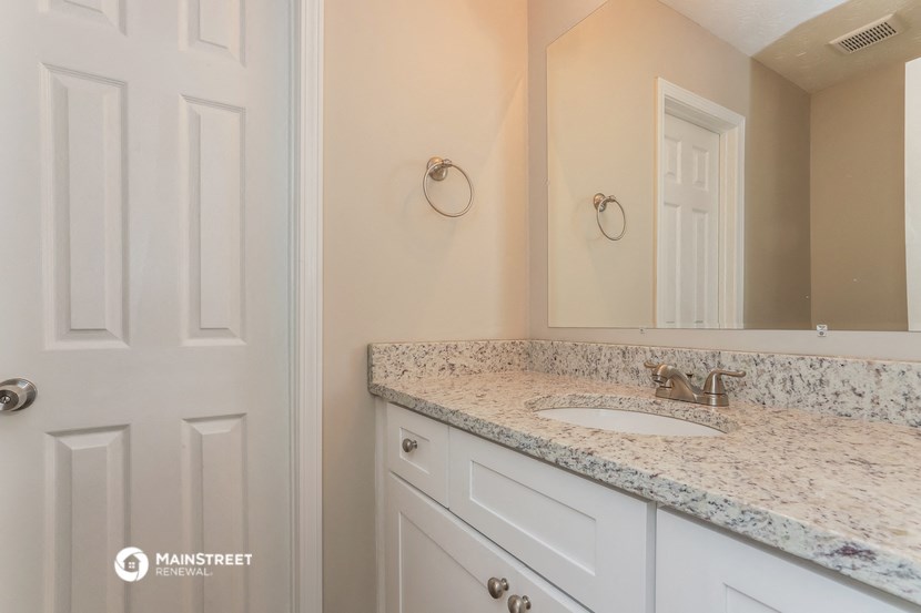 a bathroom with white cabinets and a sink and a mirror