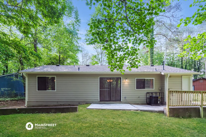 a small tan house with a yard and trees
