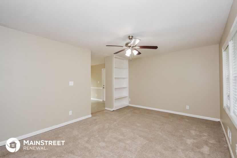 the spacious living room with carpet and ceiling fan