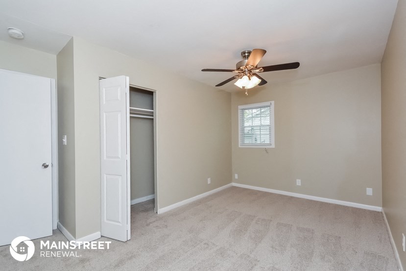 the spacious living room with ceiling fan and closet