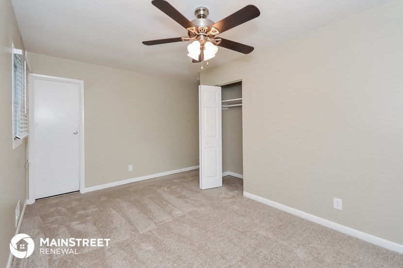 the spacious living room with ceiling fan and closet