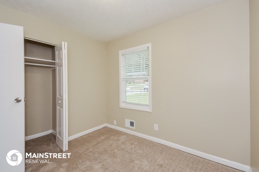 a bedroom with a closet and a window and carpeted floor