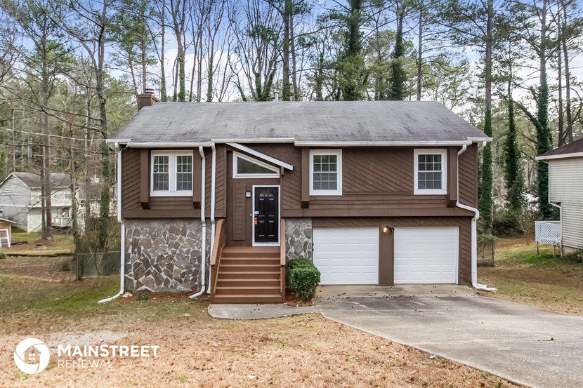 the front of a brown house with a garage and stairs