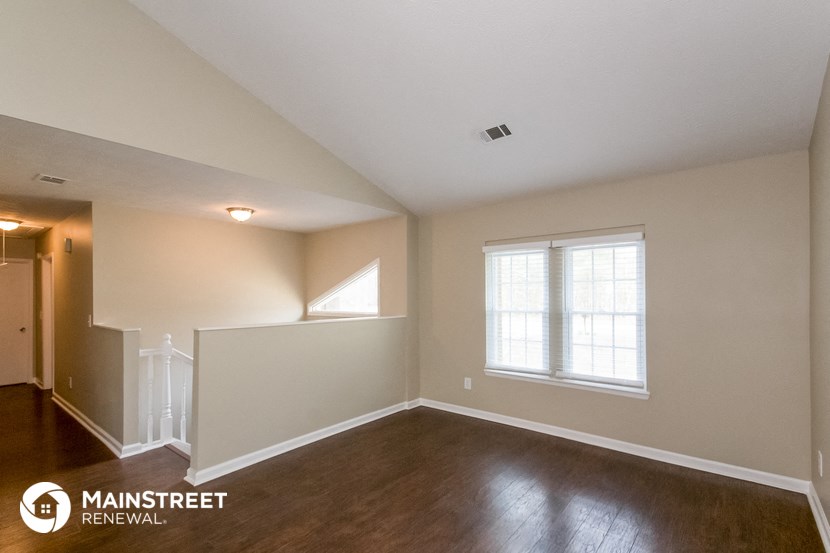 the living room of a house with wood floors and a window