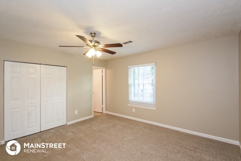 the spacious living room with carpet and ceiling fan