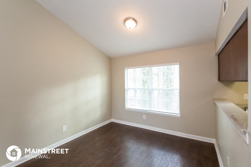 the upstairs bedroom with hard wood flooring and a large window