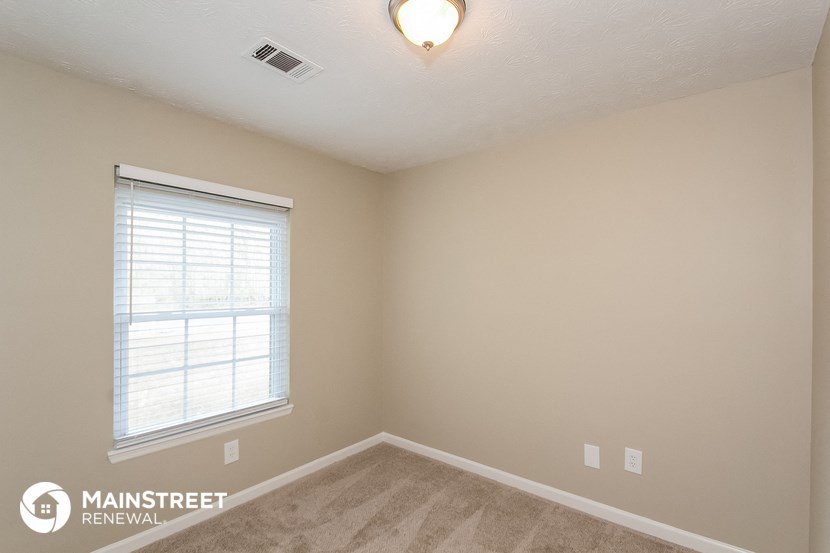 the spacious living room with a large window and carpeted flooring
