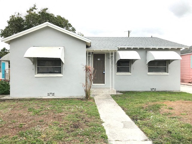 a white house with two windows and a sidewalk