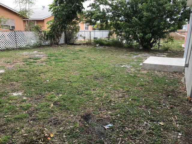 a yard with grass and a fence and some trees