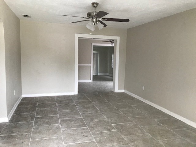 an empty living room with a ceiling fan and tiled floors