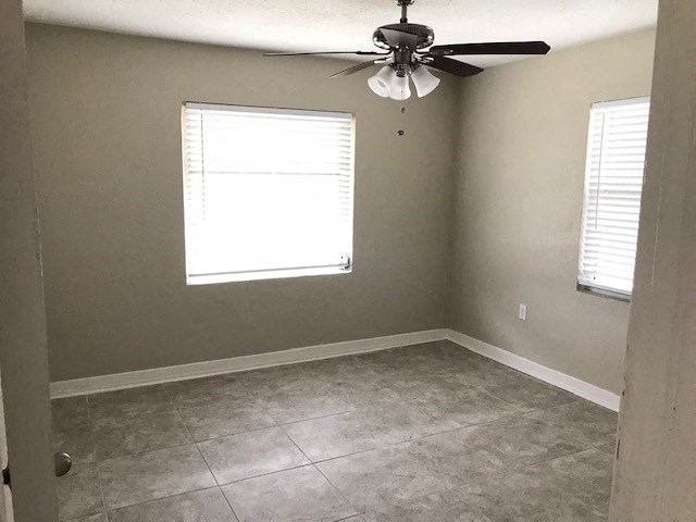 an empty room with a ceiling fan and a window